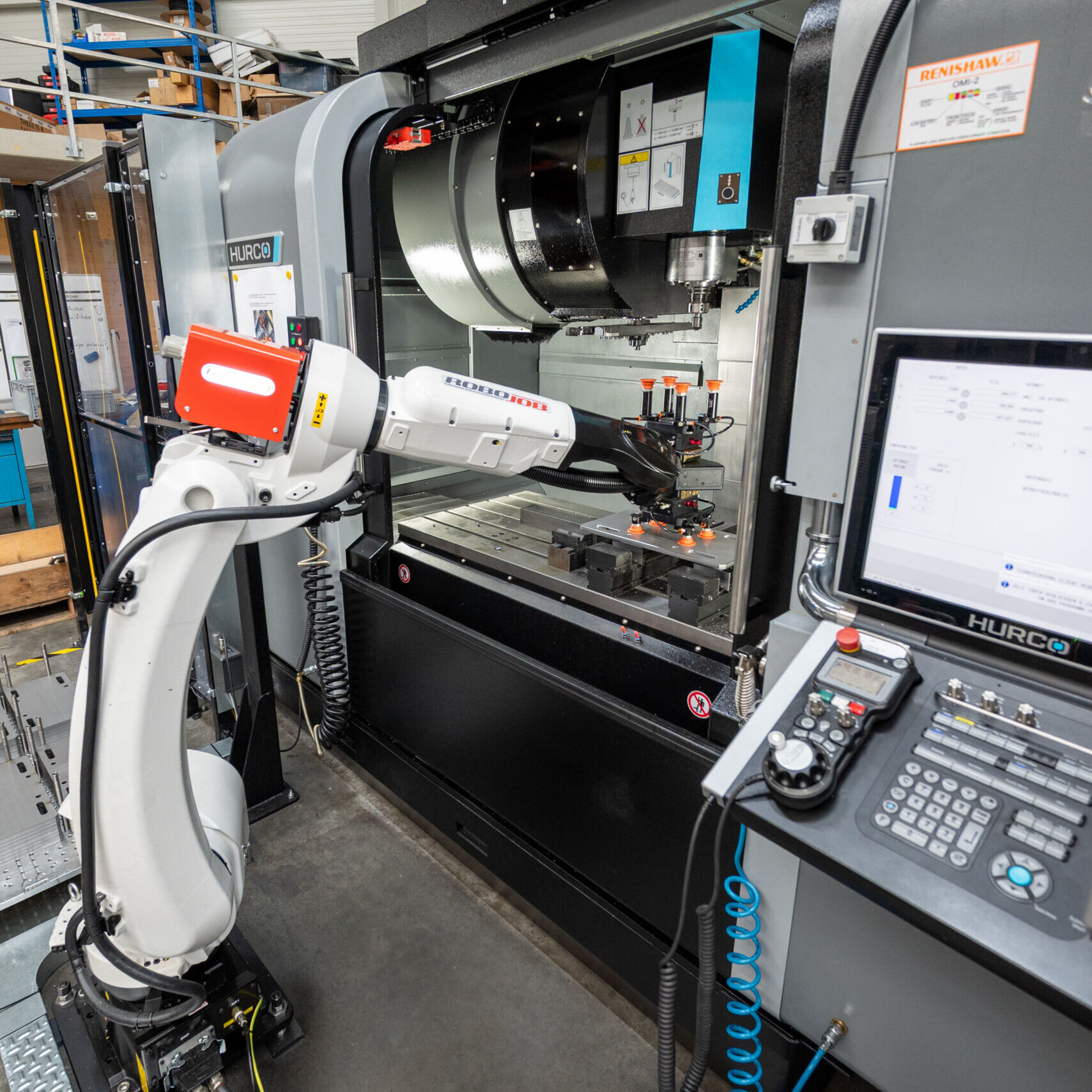 RoboJob-Roboter (schräg von oben) legt ein Werkstück in die HURCO-Anlage ein