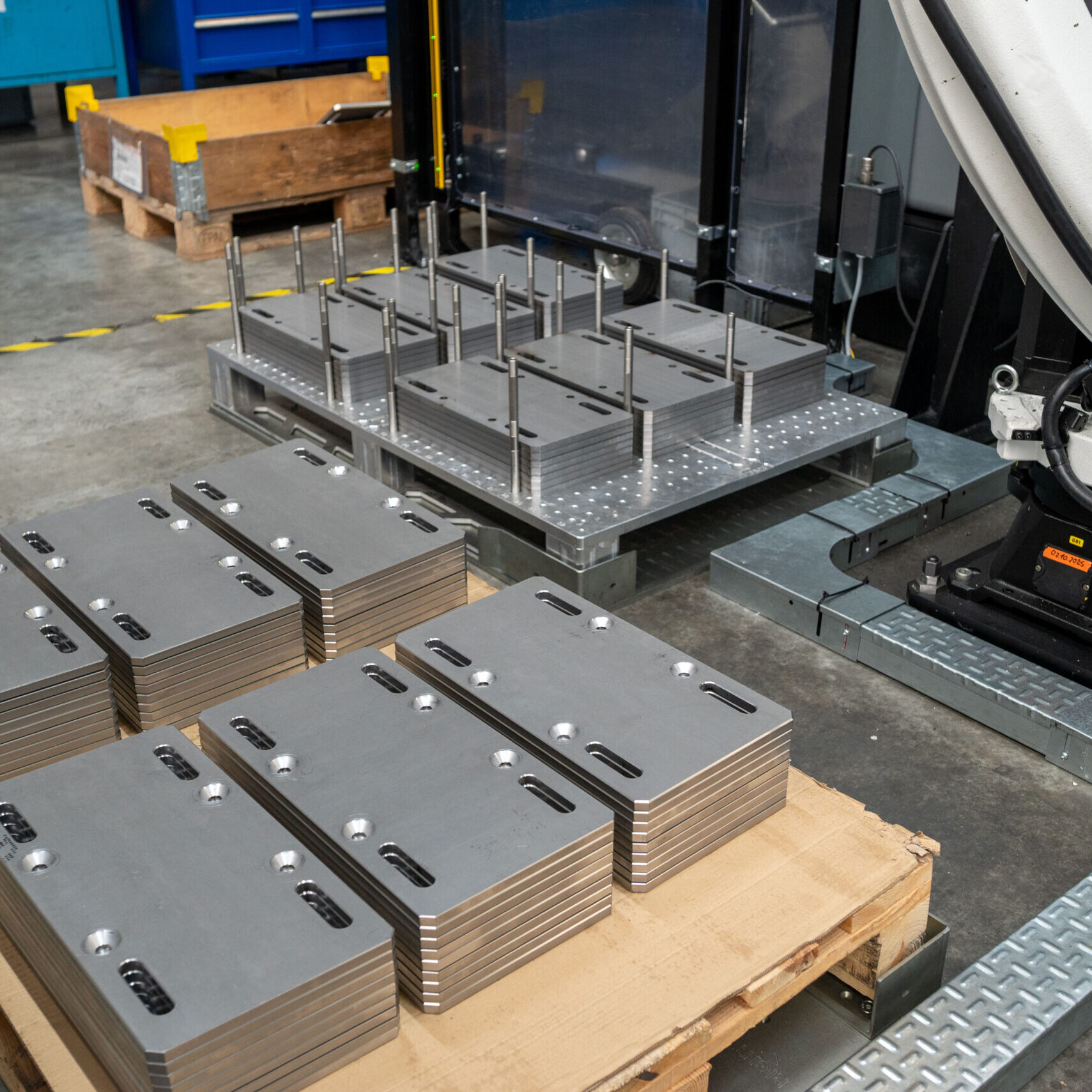 Zwei Paletten mit unbearbeiteten und fertig bearbeiteten Werkstücken