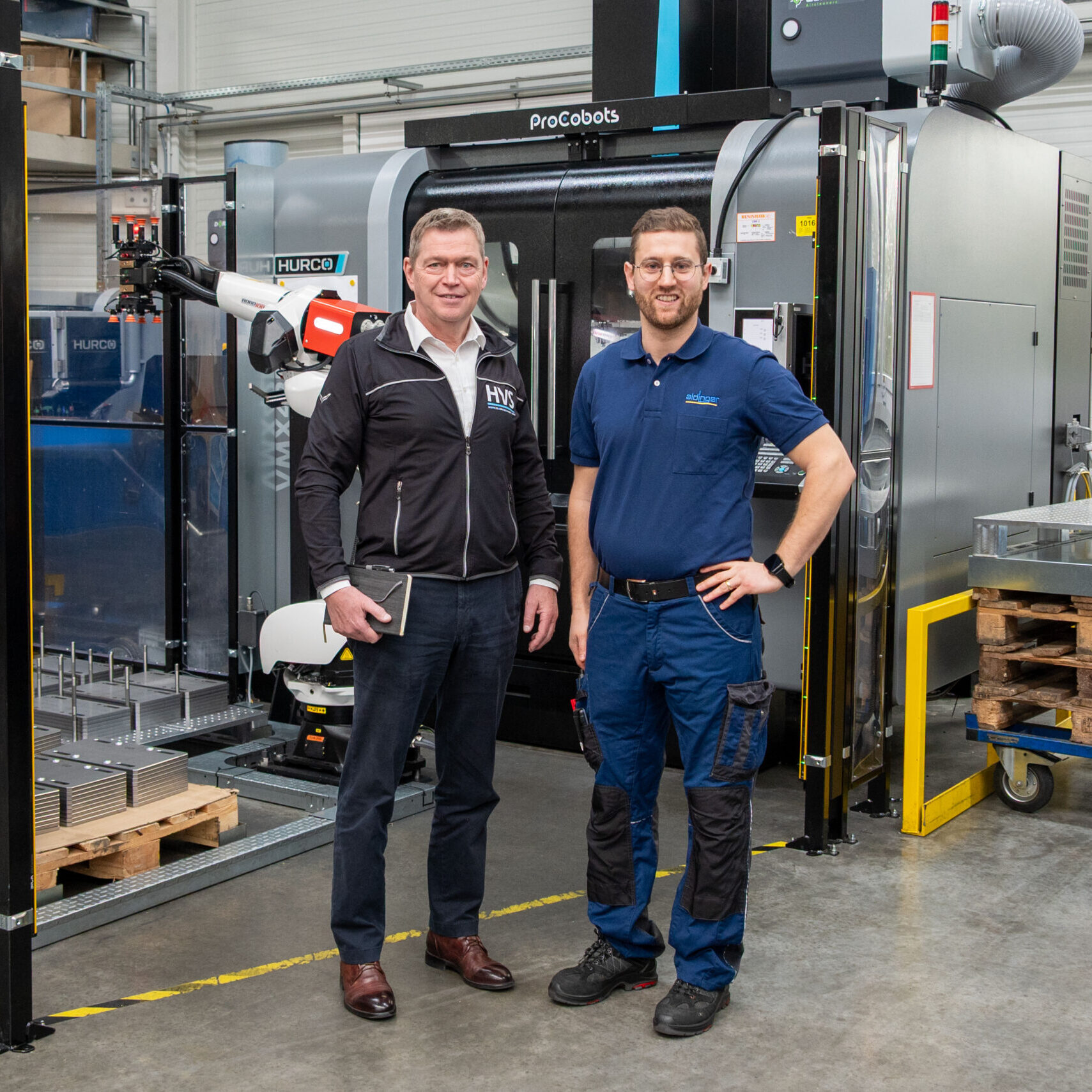 Thomas Bär (links) und Thomas Schunn vor einer Automationszelle mit Roboterhandling und Wendestation an einem 3-Achs-Bearbeitungszentrum