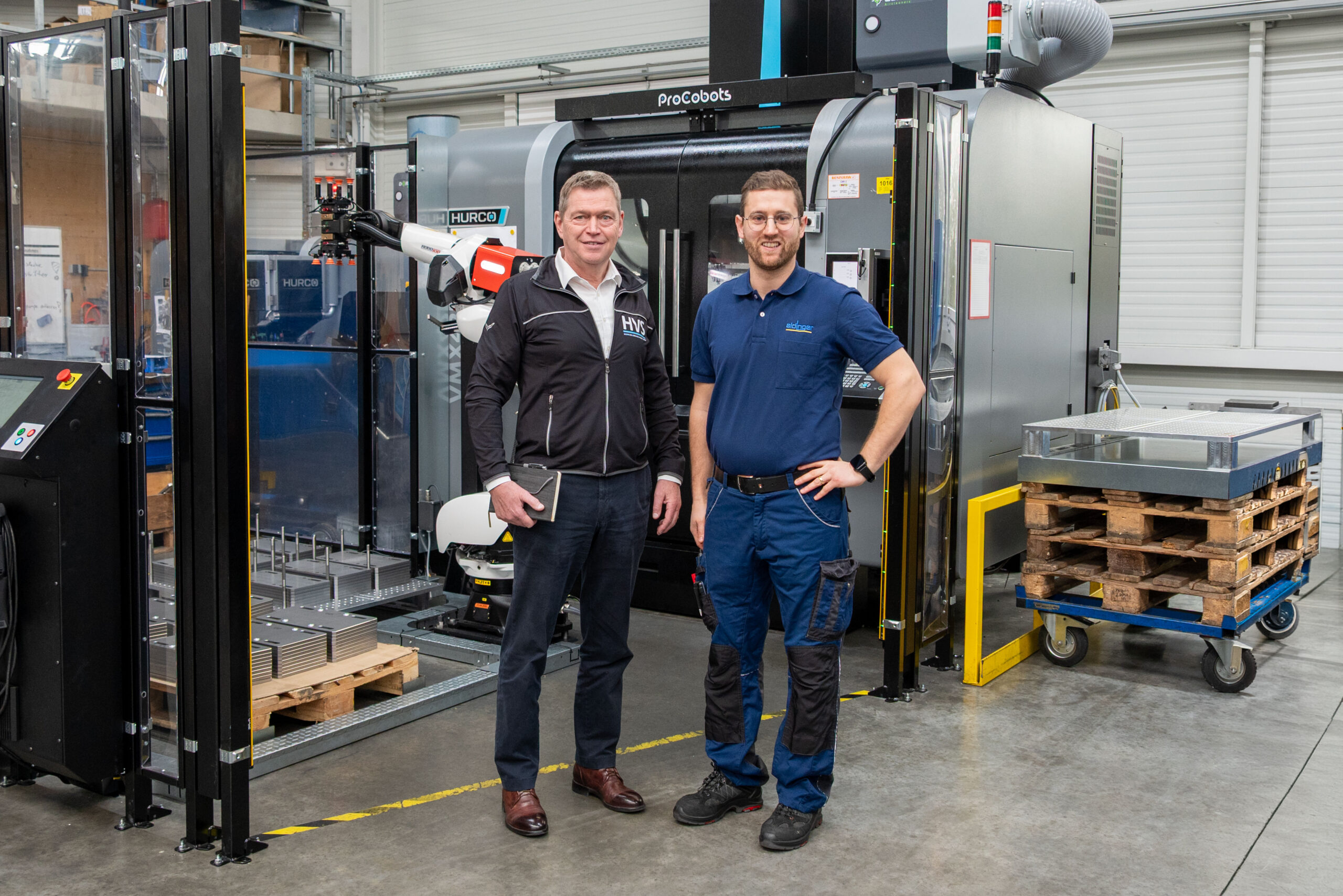 Thomas Bär (links) und Thomas Schunn vor einer Automationszelle mit Roboterhandling und Wendestation an einem 3-Achs-Bearbeitungszentrum